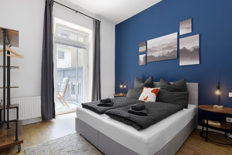 Schlafzimmer mit Queensize-Bett vor blauer Wand und Balkontür